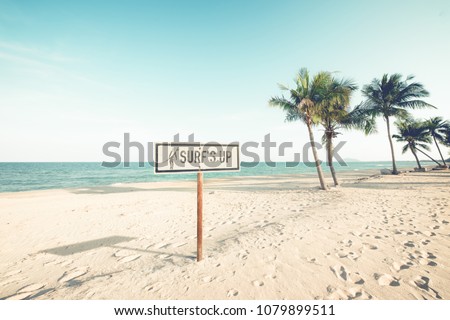 Landscape of coconut palm tree on tropical beach in summer. beach sign for surfing area. Vintage effect color filter.