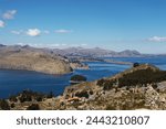 Landscape composed of blue sky with clouds, urban area, terraces and the immensity of Lake Titicaca with other islands close to Ilha do Sol in Bolivia.