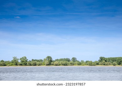 Landscape of the Danube river in Krcedin, Vojvodina, Serbia, during a sunny afternoon, facing a green forest on the riverbank. The Danube is the biggest river on Central Europe.