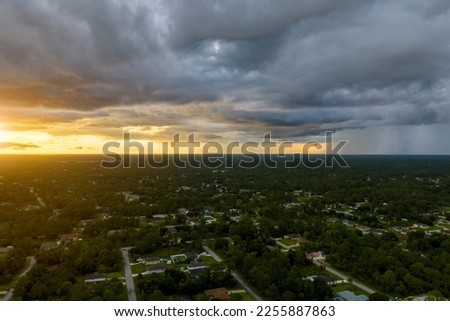 Landscape of dark ominous clouds forming on stormy sky during heavy thunderstorm over rural town area at sunset