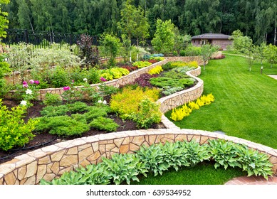 Landscape design with flower beds, natural landscaping panorama in home garden. Beautiful view of nice landscaped garden in residential backyard. Scenery of landscaping area in summer. 
