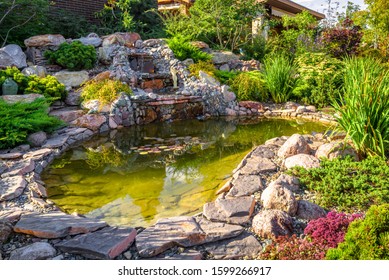 Landscape Design In Home Garden, Beautiful Landscaping With Small Pond And Waterfall. Landscaped Place With Stones And Water At Country House. Nice Pond And Fountain In Backyard Or Yard In Summer.