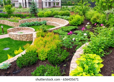 Landscape Design In Home Garden, Landscaping With Flowerbed And Stones In Backyard. Beautiful Upscale Landscaped Residential Back Yard. Landscape Of Retaining Walls And Flowers. Horticulture Theme.