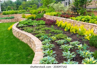 Landscape Design In Luxury Back Yard Of Residential House, Landscaping Of Nice Home Garden. Beautiful Landscaped Backyard With Retaining Walls And Plants In Summer. Nature And Horticulture Concept.