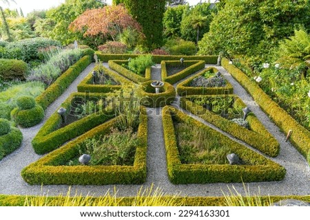 Landscape design manicured box hedge garden triangular arrangement surrounding herb gardens.