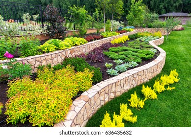 Landscape design of nice home garden, natural landscaping with decorative stones in residential house backyard. Luxury flowerbed and beautiful plants in summer, green upscale landscaped back yard.