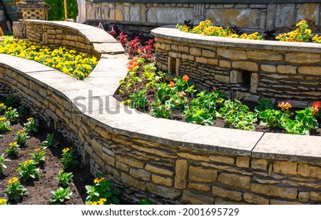 Landscape design of nice home garden, landscaping with retaining walls and flowerbeds in residential house backyard. Beautiful landscaping outdoor in summer, flowers and plants in landscaped yard. 