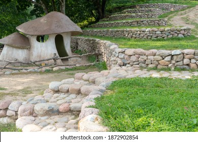 Landscape design. Stepped terrace secured with raw stones. Hobbit village. Designer house in the form of a large mushroom.