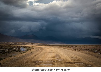 Landscape with dirt road in the mountains under stormy sky.Rural mountain road in Peru, South America, just before the snow storm. Mountains in the background.