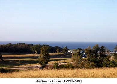 Landscape of fields and small house structures next to the ocean