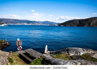 Landscape In The Fjord With A Diving Board In The Foreground, A Rescue Buoy And Bergen, Norway In The Background 