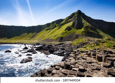 Landscape of Giant's Causeway trail with a blue sky in summer in Northern Ireland, County Antrim. UNESCO heritage. It is an area of basalt columns, the result of an ancient volcanic fissure eruption - Shutterstock ID 1897449034