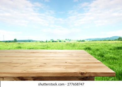 landscape of grass and sky of blue color with table of wood 