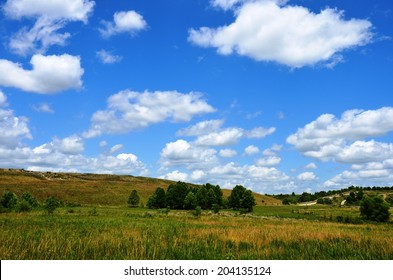 Landscape With Green Grass, Trees, Blue Sky And Clouds On Reclaimed Mining Area.