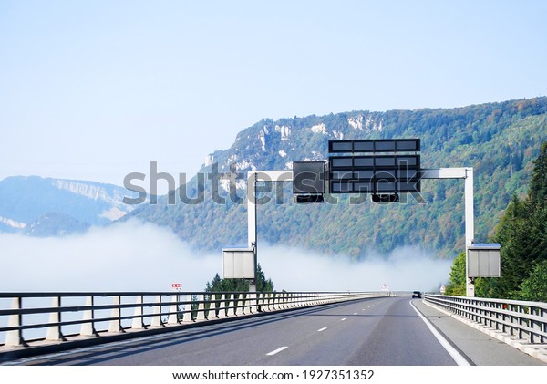 Landscape highway, toll or autoroute in France\
with front view bridge, board, moutain and foggy in sunny day.\
Holiday and transport concept. Non\
focus.