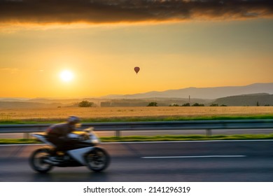 Landscape with hot air balloon and motion blurred motorcycle at sunset - Shutterstock ID 2141296319