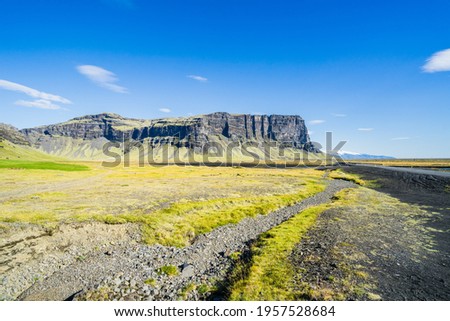 The landscape of Iceland in the Kalfafell region with stones in grass against a blue sky