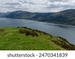 A landscape image of Long Loch in the Scottish Highlands.  From an elevated view across the water can be seen a Salmon Farm, while mountains rise high in the distance.