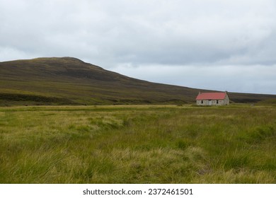 A landscape image of a remote cottage, Known as The Red House, at the end of Glen Geldie in the Scottish Highlands.  High mountains rise to the left of the grassy plain in which the building stands. - Powered by Shutterstock