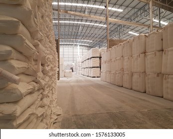 Landscape inside a warehouse with white color tons of sack or bag stacking up under the roof. Agricultural products being processed and ready for the export shipment. Industrial and factory concept.