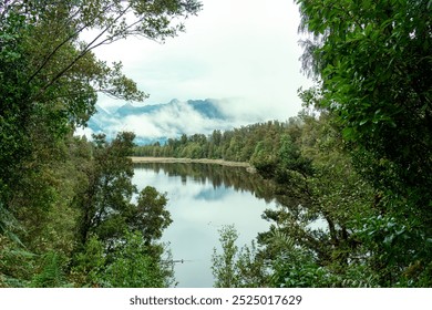 Landscape of Lake Matheson glacier lake with rainforest covered and mountain range, foggy reflection at South Westland, New Zealand - Powered by Shutterstock