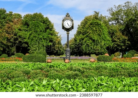 Landscape with the main entrance with vivid green plants, green lime trees and grass in a sunny summer day in Cismigiu Garden in Bucharest, Romania