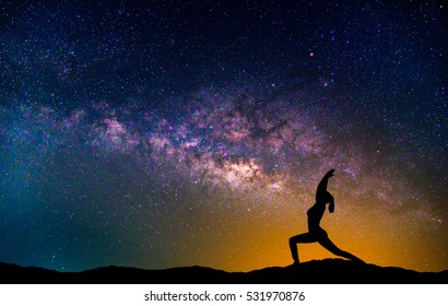 Landscape With Milky Way Galaxy. Night Sky With Stars And Silhouette Woman Practicing Yoga On The Mountain.