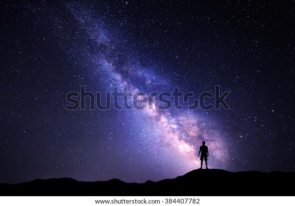 Landscape with Milky Way.\
Night sky with stars and silhouette of a standing happy man on the\
mountain.