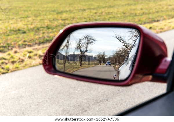 Landscape in the mirror of a car. Image of\
landscape on side car mirror, Concept Travel. Looking out the car\
window at the rearview\
mirror