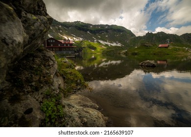 Landscape with mountain lake, cabin and steep ridge. Located in Fagaras Natural Park, Transylvania, Romania.