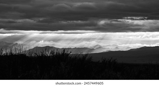 Landscape with a mountain range and the rays of the sun breaking through the storm clouds