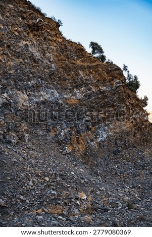 landscape of a mountain slope with sparse vegetation and layers of limestone rocks