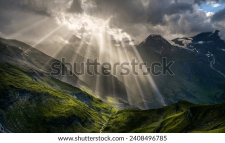 Landscape and nature in the spring. Landscape with dramatic sky and green meadows. The sun rays through the clouds. The Hohe Tauern mountain range, the valley below the hochalpenrstrasse.