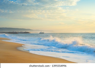 Landscape with the ocean beach, fishing ship at beautiful sunset. Nazare, Portugal