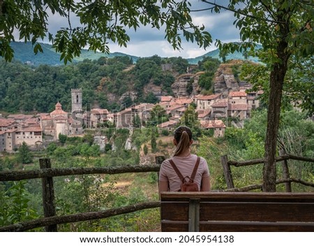 Landscape of the old town of Rupit in Catalunya, there is a bench and a young girl sitting looking at the landscape