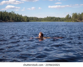 Landscape On A Forest Lake With A Woman Swimming In The Water