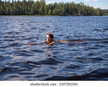 Landscape On A Forest Lake With A Woman Swimming In The Water