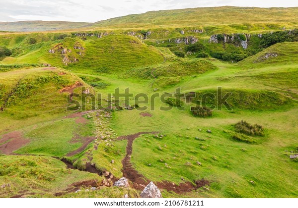 Landscape\
on the Isle of Skye in Scotland. Meadows of Fairy Glen with central\
circles on the green. Small hills with bushes and clouds in the\
sky. Well-trodden paths with earth in\
summer.