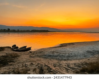 Landscape with a overview of the river side with a beautiful colored sunset with boats at the river shore