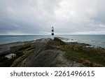 Landscape panorama view of black and white Cape Campbell lighthouse on pacific ocean beach in Lake Grassmere Marlborough South Island New Zealand