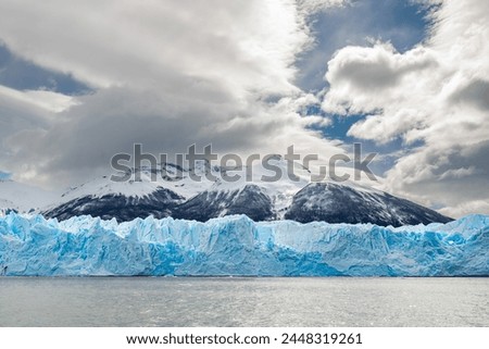 Landscape of the Perito Moreno glacier, with its majestic blue ice wall and snowy mountains in the background on a cloudy day