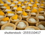 A landscape photo of preparing Fruit Pies dessert. Some pieces are already filled in with sweet fla and Mango slice.