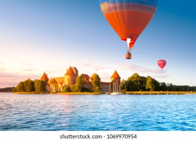 Landscape with red brick castle on island and flying air balloon in Trakai