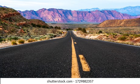 Landscape Of A Red Rock In Mountain In Gunlock, Utah With Empty Road Leading Line Shot At Low Angle At Sunset