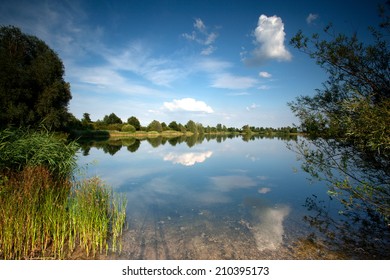 Landscape with reflections of the sky, clouds and trees  in the water of a lake