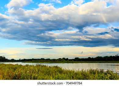 Landscape with river, plants and dramatic clouds on the sky