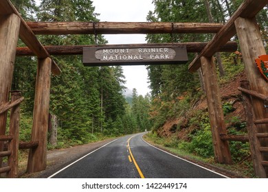 Landscape Of Road Into Forested Area With Large Sign For Mount Rainier National Park