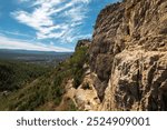 landscape of Rocky Cliffside Path Overlooking Lush Green Valley with Expansive Sky View