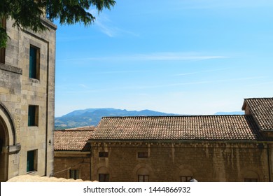 Landscape and rooftops of San Marino buildings in front of the blue sky and mountains during the summer time - Powered by Shutterstock