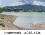 landscape of sand shore of Pertusillo lake with Spinoso uphill village in background, shot in bright summer light , Agri valley,  Potenza, Basilicata, Italy
